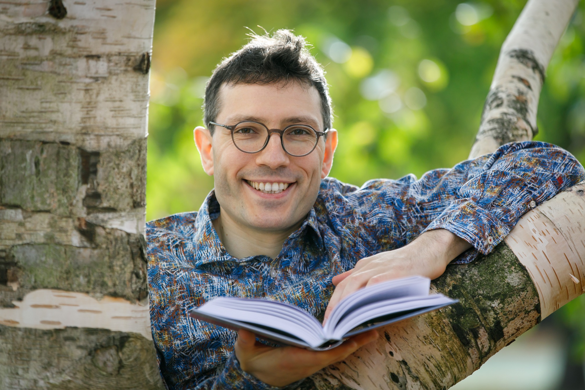 Evgenij Unker an einem Baum mit Buch.